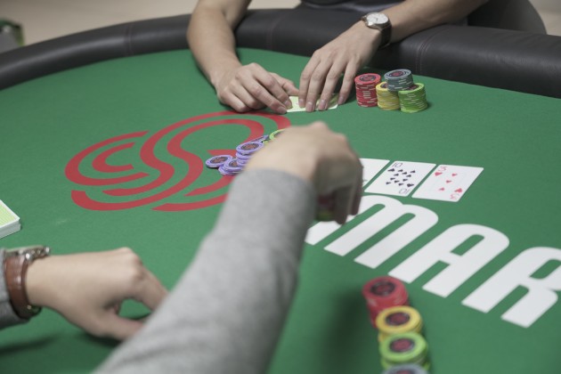 A hand making a bet at a poker table