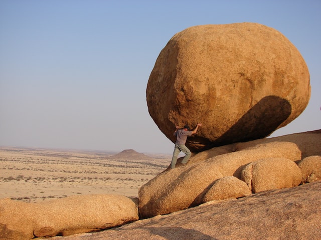 A picture of person trying to move a big rock, representing the mindset strength