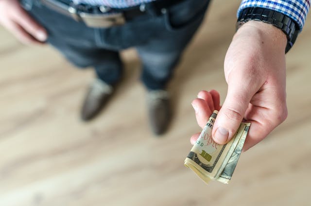 A person handing money representing the poker term "rakeback"